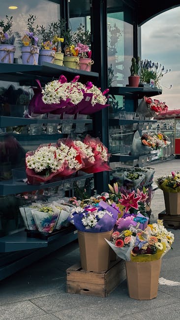A display of various floral arrangements and bouquets in a florist shop, featuring a range of fresh flowers including white chrysanthemums, pink and purple lilies, and assorted mixed blooms wrapped in