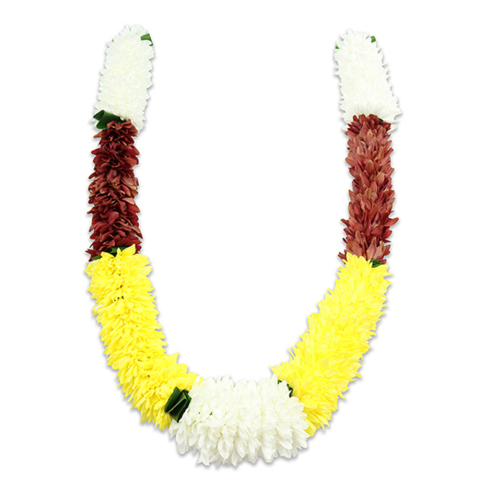 Carefully composed by local hands, this U-shaped ceremonial garland is shown on a pure white field with a soft shadow that helps reveal its layered texture. Constructed from thousands of tiny fabric petals, the garland faithfully reproduces the look of natural blooms while offering durability for repeated ceremonial use. Each symmetrical arm opens with a compact, cylindrical cluster of creamy white petals-reminiscent of miniature chrysanthemums or jasmine pom-poms-creating an ethereal, auspicious starting point. Directly below, a concentrated band of deep maroon or reddish-brown provides a rich counterpoint, its tightly packed petals giving weight and depth. The longest and most expressive portion of each arm is a generous sweep of bright yellow clusters, worked to resemble plush marigolds and sweeping in a cheerful arc that attracts the eye. At the curve's lowest point, a generous central cluster of pure white chrysanthemum-like blooms unites the two sides, while small dark green leaf-like accents mark the transitions and lend a touch of organic contrast. As a local Hanwell florist I recognise how this palette-white for purity, yellow for prosperity, maroon for devotion-functions in rituals, from temple offerings to wedding entrances and Diwali decorations near Boston Manor or along Uxbridge Road. Made by Flower Delivery Hanwell artisans with meticulous layering and attention to proportion, the garland reads as a respectful, time-honoured piece meant to honour tradition and ceremony in community life.